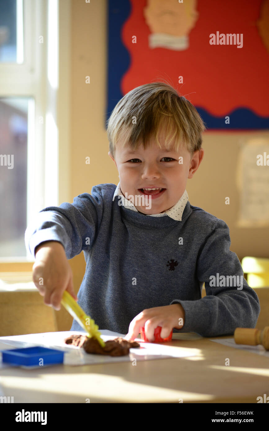 Un petit Garçon jouant avec de la pâte à modeler à l'école maternelle. Banque D'Images