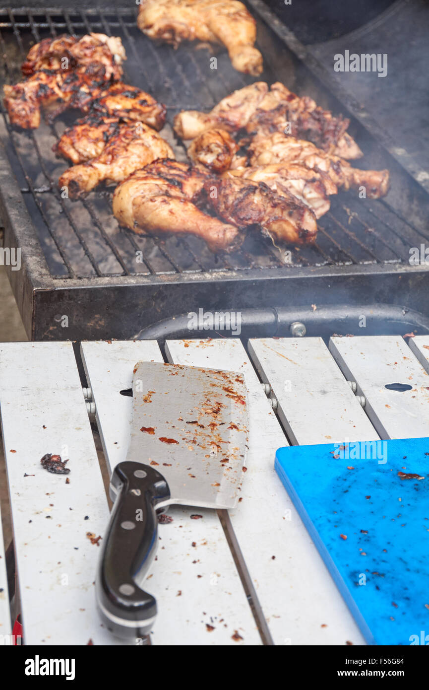 poulet sur un barbecue avec un fleaver de viande sale en premier plan Banque D'Images