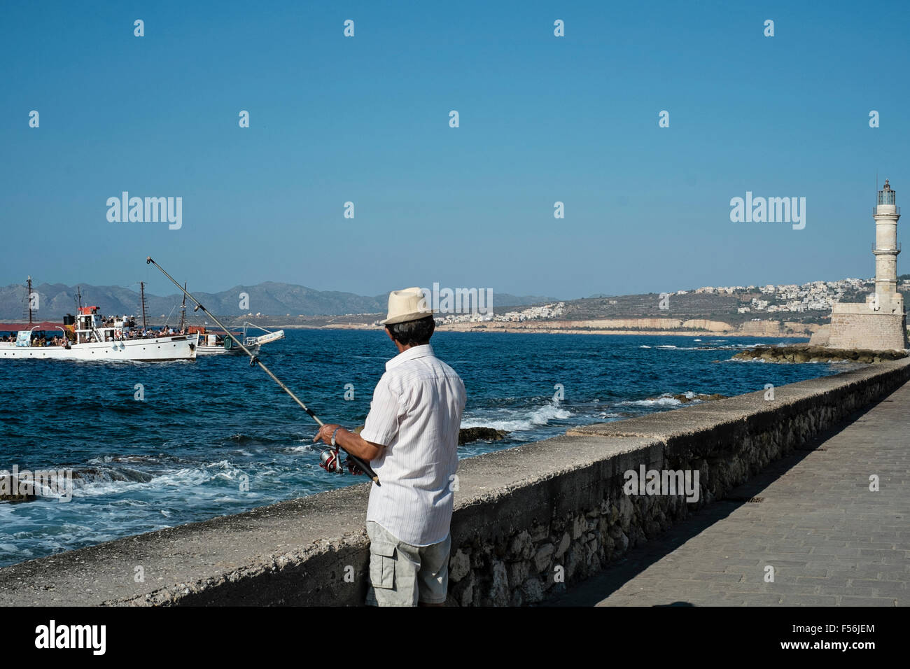Un pêcheur tente sa chance patiemment le long du front de mer de La Canée en Crète en Grèce Banque D'Images