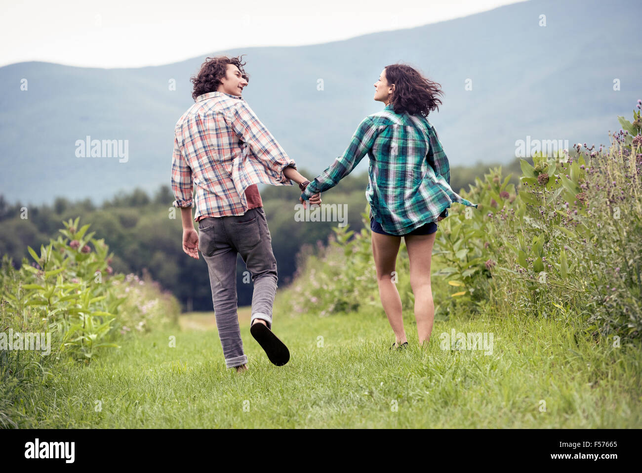 Un couple, homme et femme qui traverse une prairie main dans la main. Banque D'Images