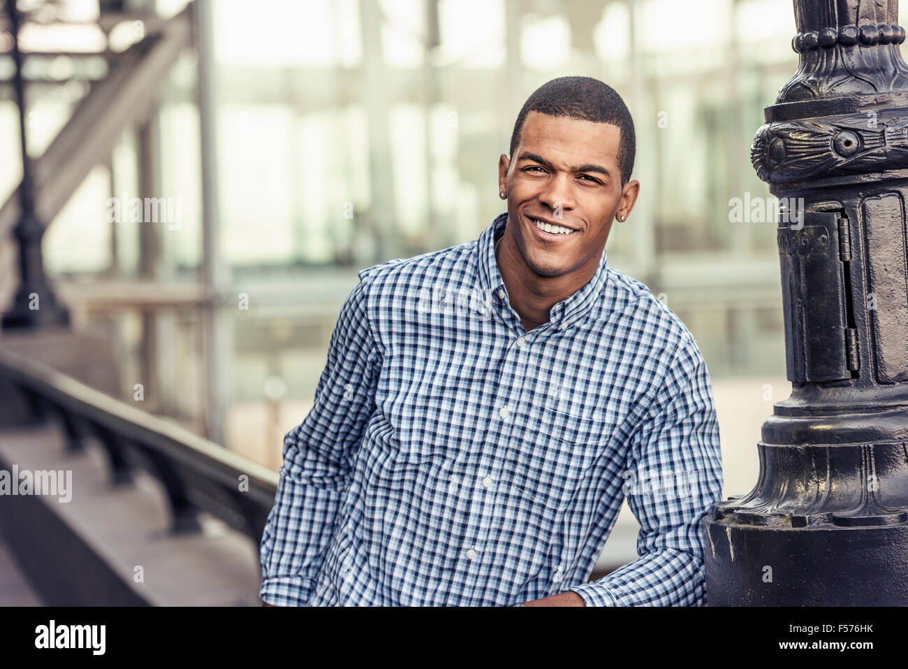 Un homme en chemise bleue s'appuyant sur une balustrade dans un parc de la ville Banque D'Images