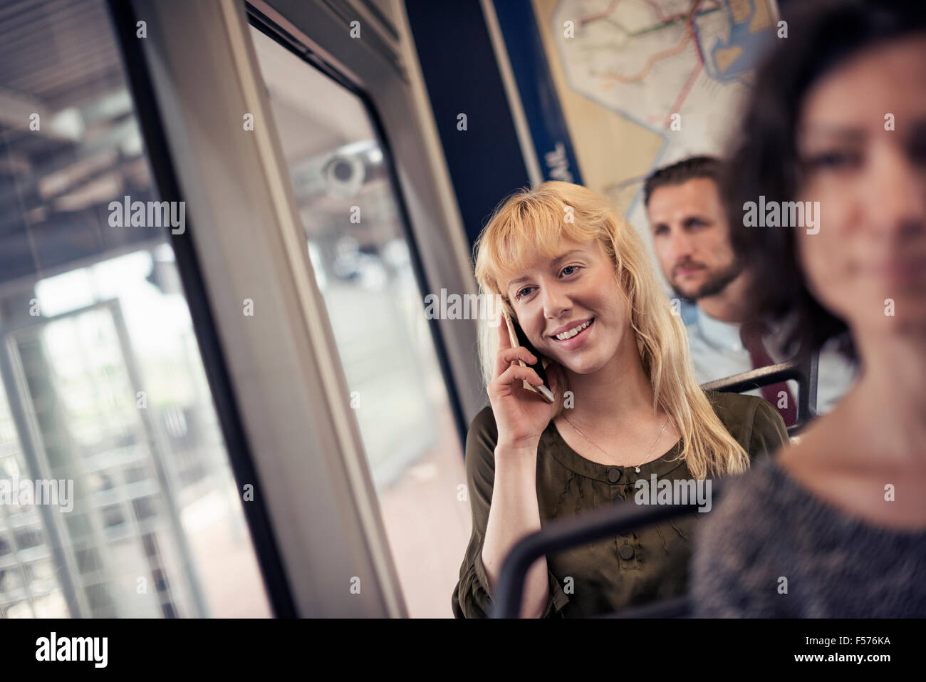 Une femme blonde sur un autobus de la ville, à parler sur son téléphone intelligent Banque D'Images