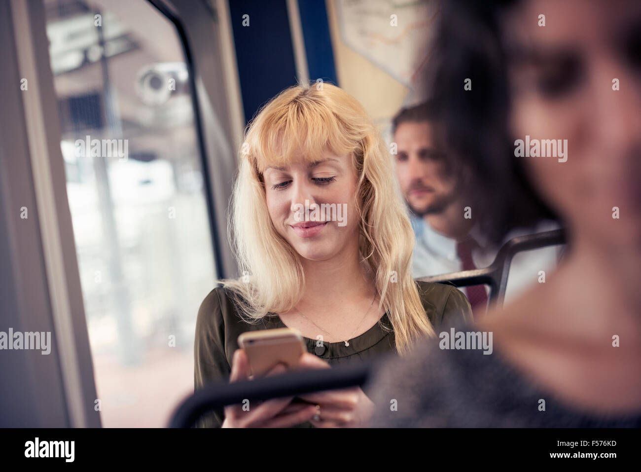 Une femme blonde sur un bus en regardant son téléphone portable Banque D'Images