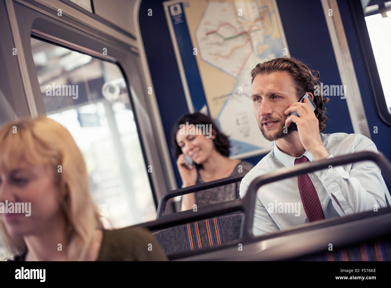 Trois personnes dans un bus, deux de parler sur leur téléphone cellulaire Banque D'Images
