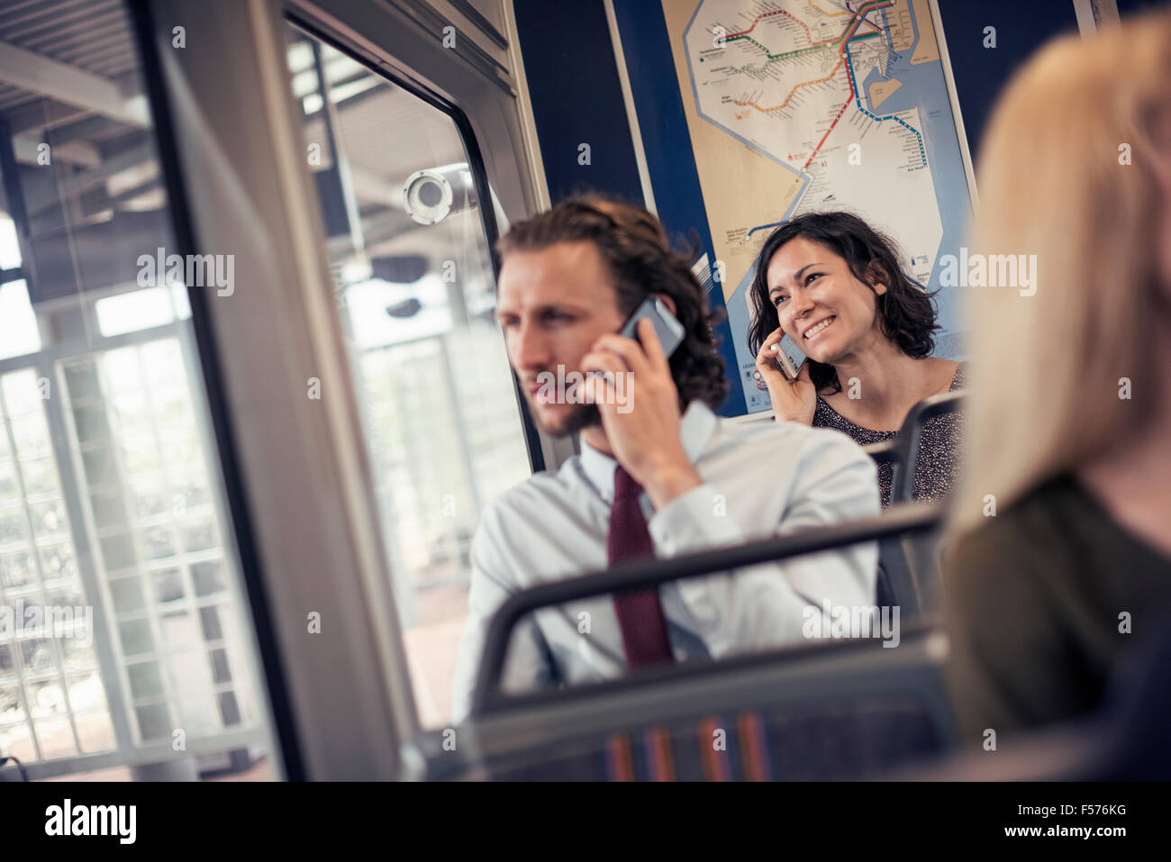 Deux personnes assises sur un bus de parler sur leur téléphone cellulaire Banque D'Images