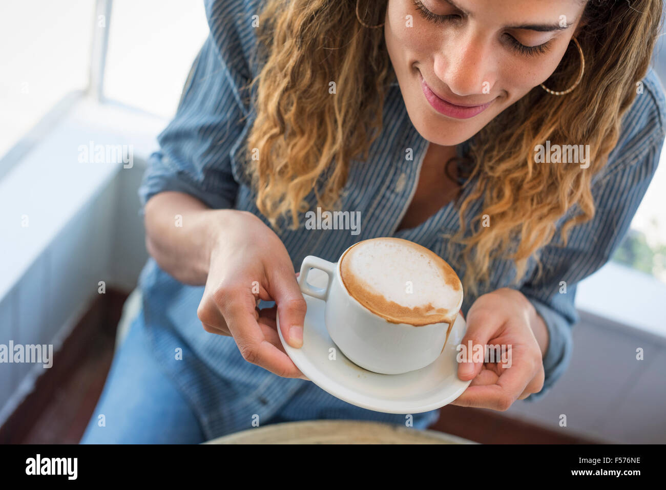 Une femme tenant une tasse de café dans un café. Banque D'Images