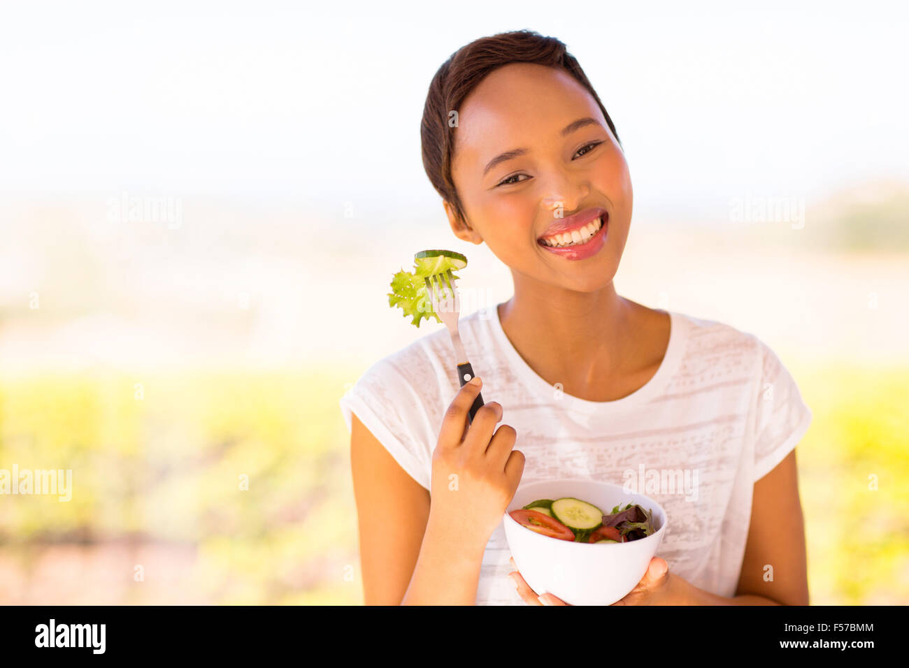 Pretty young woman eating salad extérieur noir Banque D'Images