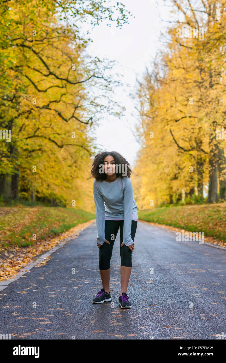Belle mixed race African American girl teenager woman jogging marche fitness en automne les arbres d'automne Banque D'Images