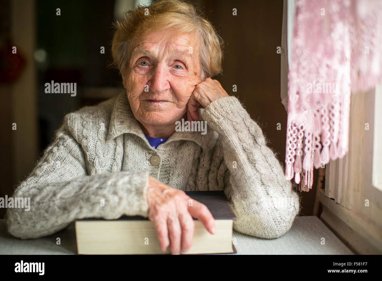 Une vieille femme assise avec un livre à la table Photo Stock Alamy Une vieille femme assise avec un livre à la table Photo Stock Alamy