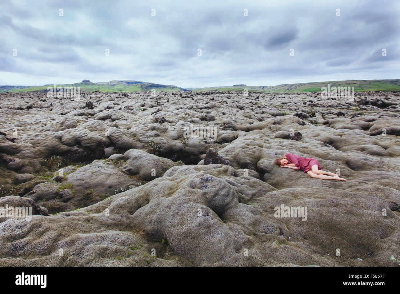 Belle jeune fille en robe rouge dormant dans champ de lave en Islande, la solitude concept Banque D'Images Belle jeune fille en robe rouge dormant dans champ de lave en Islande, la solitude concept Banque D'Images