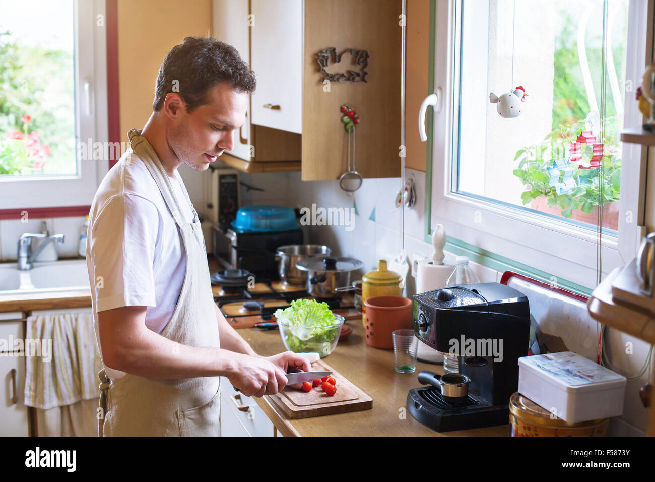 La cuisson des aliments sains, jeune homme couper les tomates dans la cuisine Banque D'Images