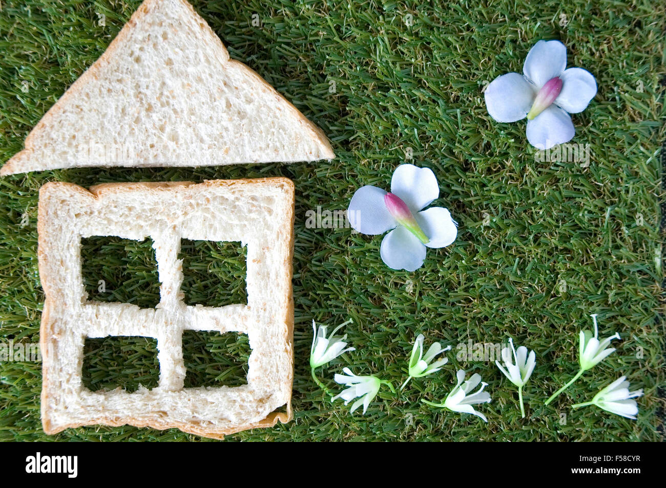 Couper le pain en forme de maison avec des fleurs de jardin Banque D'Images