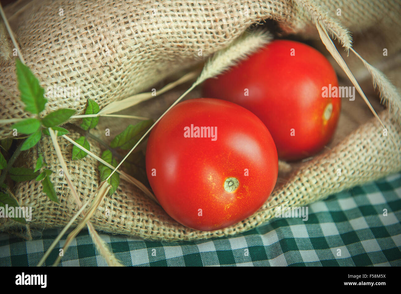 Tomates rouges mûres sur un fond de toile de jute. Banque D'Images