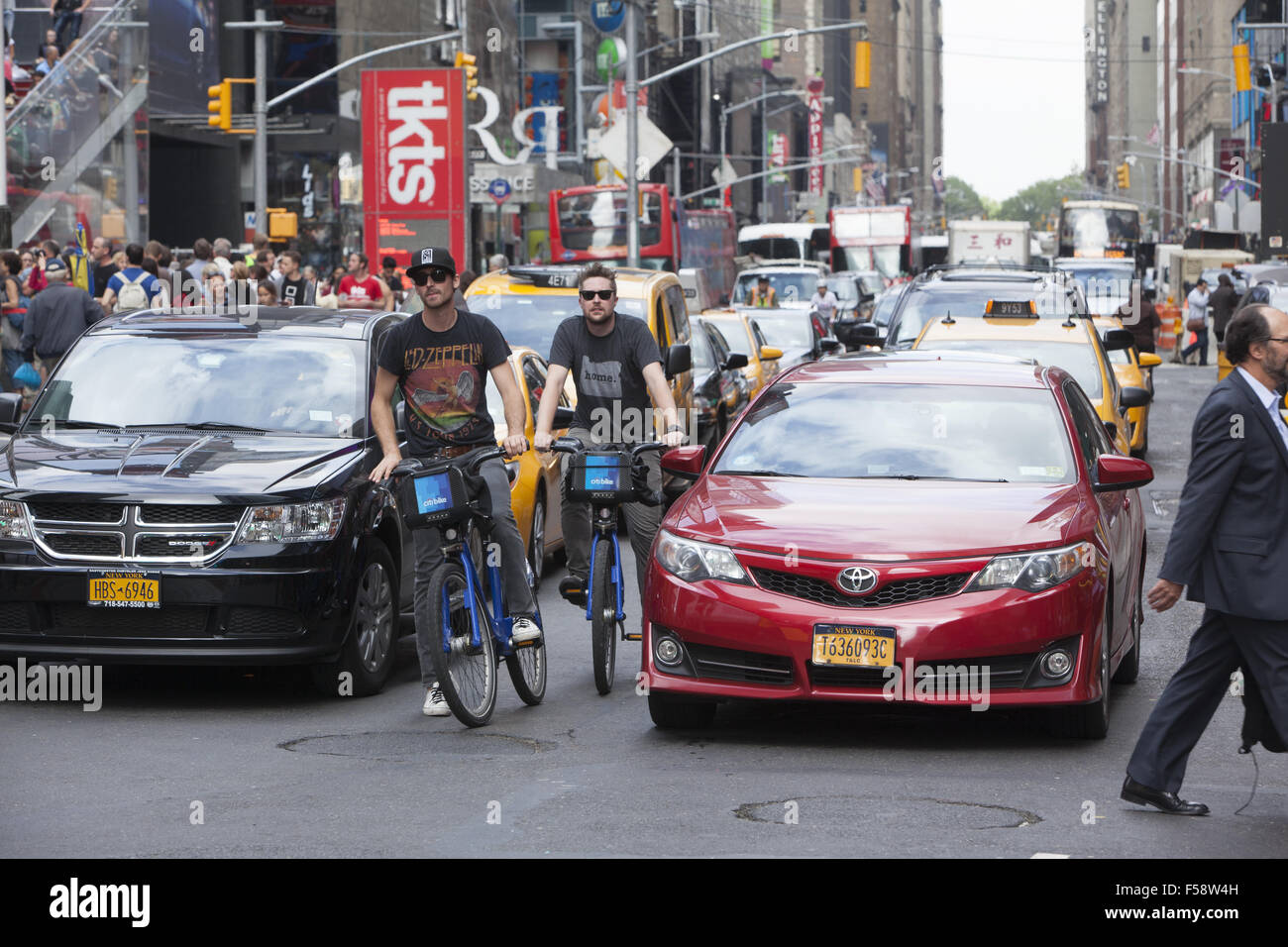 De braves gens roulent au milieu de la circulation constante de din sur la 7e Avenue à Times Square, New York. Banque D'Images