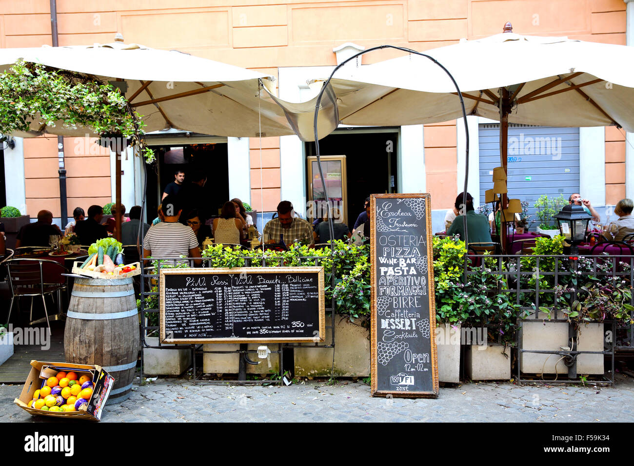 Diners avoir une saine alimentation à l'extérieur dans un osteria in Trastevere pendant une soirée d'été à Rome Banque D'Images Diners avoir une saine alimentation à l'extérieur dans un osteria in Trastevere pendant une soirée d'été à Rome Banque D'Images