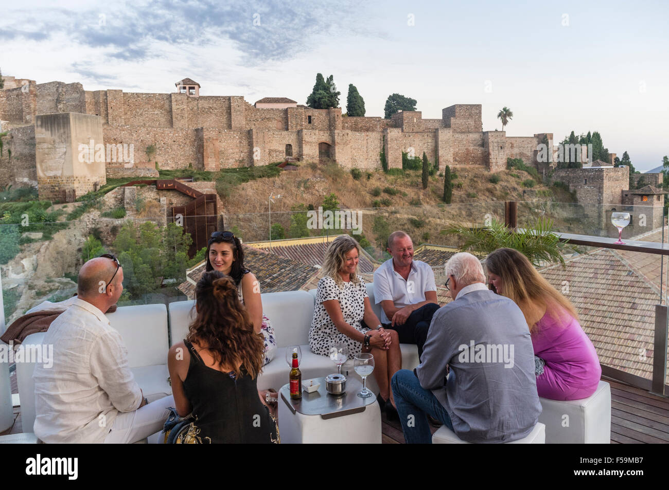 Les gens avec l'Alcazaba château en arrière-plan au bar-salon sur le toit de l'Alcazaba Premium Hostel, Malaga, Andalousie, espagne. Banque D'Images