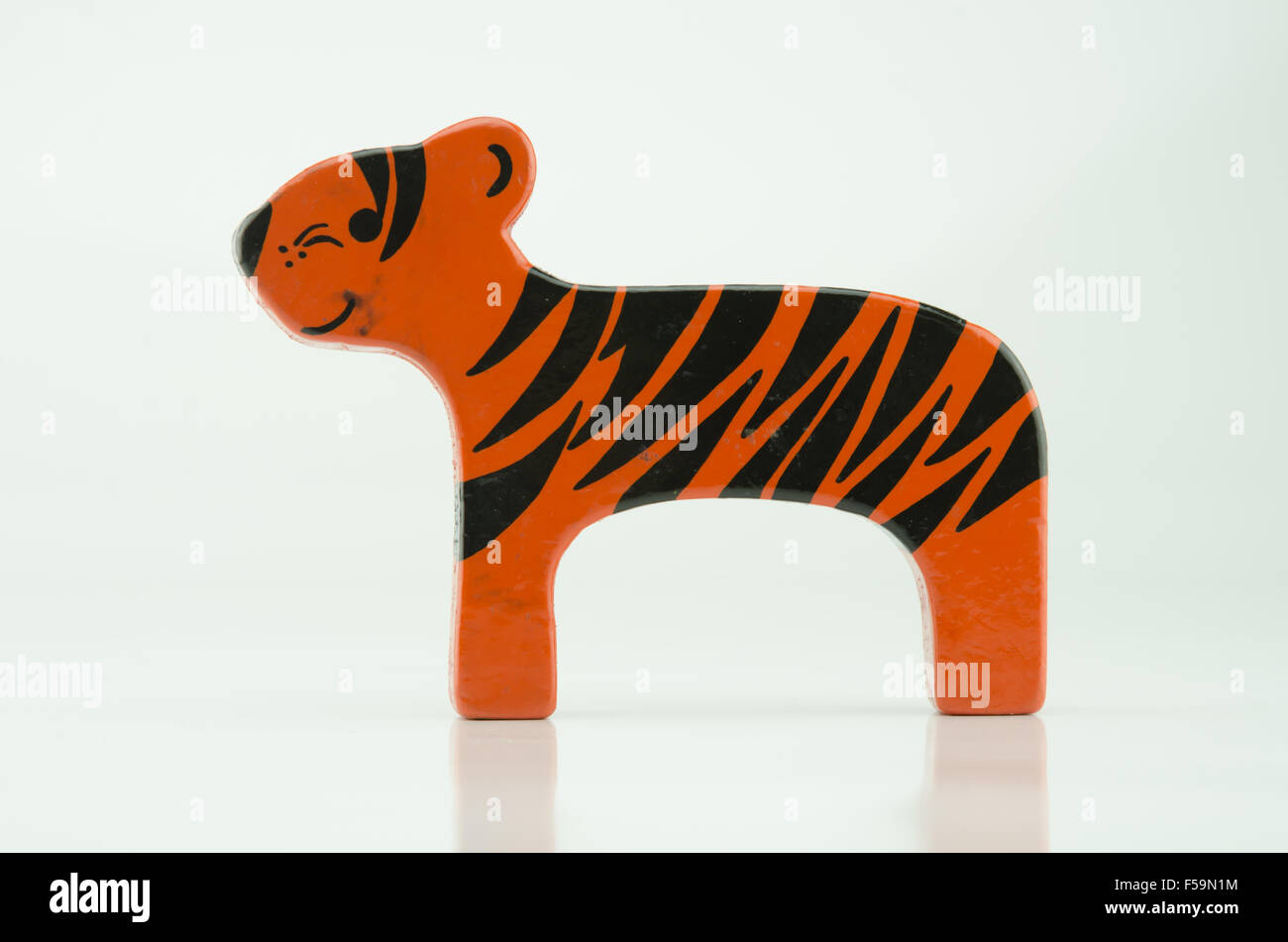 Un jouet tigre en bois peint sur un fond blanc. Banque D'Images