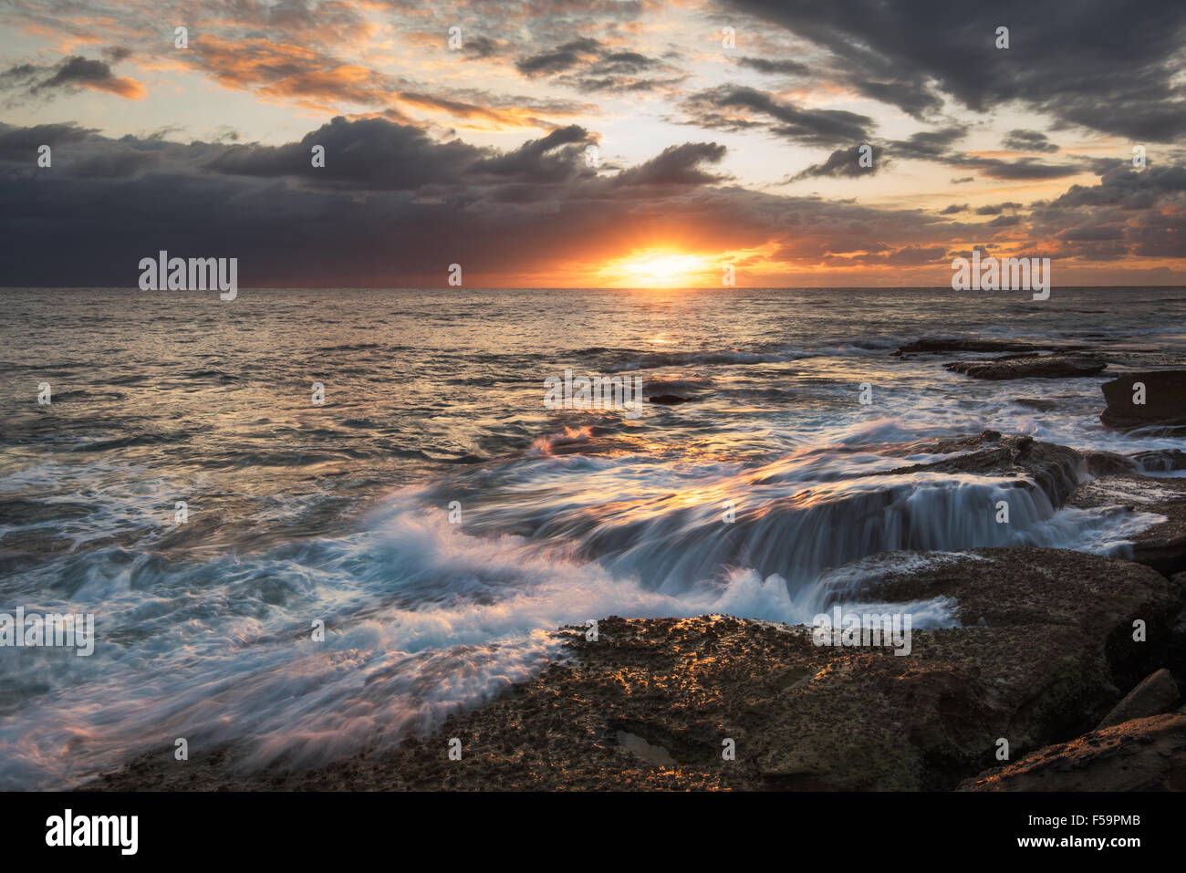 Seascape sunrise longue exposition avec chute d'eau et plus rock avec Sun Bright Sky Banque D'Images