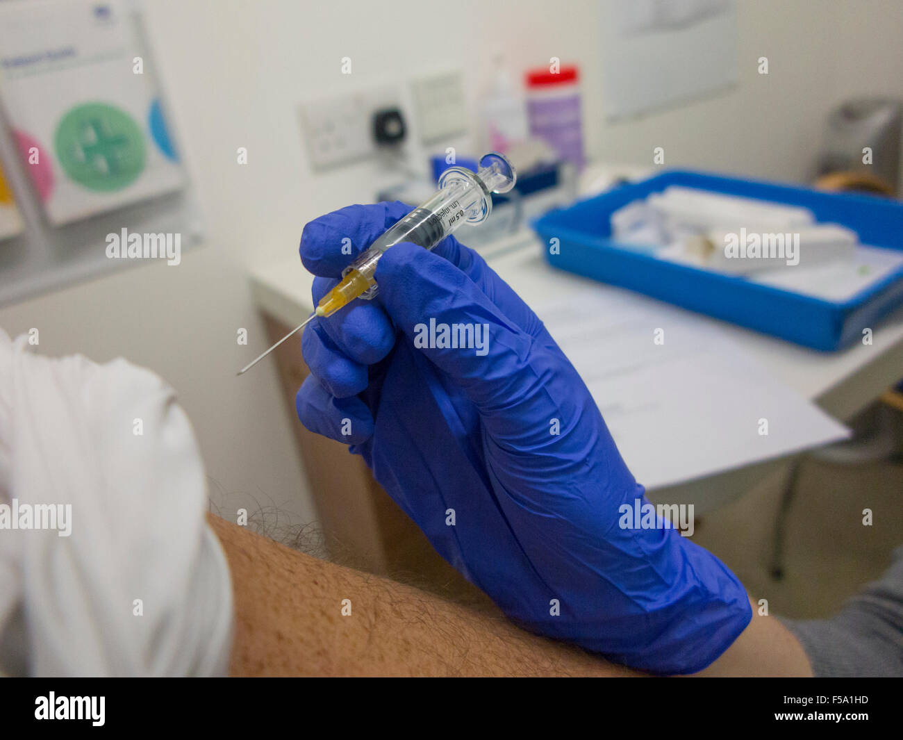 Un homme roule dans sa manche afin d'avoir une grippe jab pour le protéger contre la grippe pendant l'hiver Banque D'Images