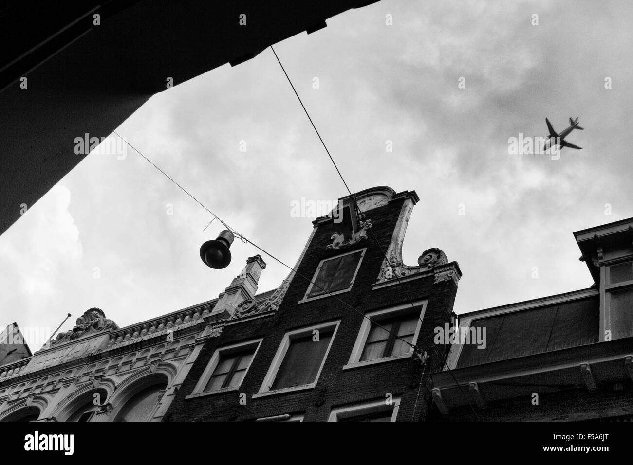 Un avion volant à basse altitude au-dessus autre type d'architecture à Amsterdam, Holland Banque D'Images