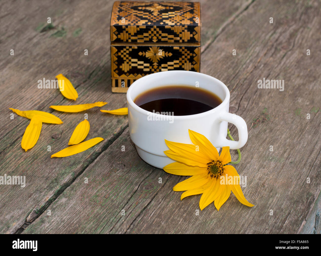 Cercueil, pétales, fleur jaune et le café, sur une table en bois, une nature morte Banque D'Images
