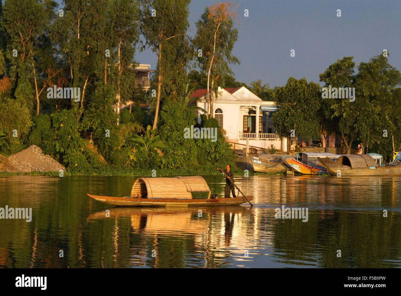 Un sampan en bois fait son chemin jusqu'à la protection des eaux brunes de la rivière des Parfums à Hue, Vietnam. Banque D'Images