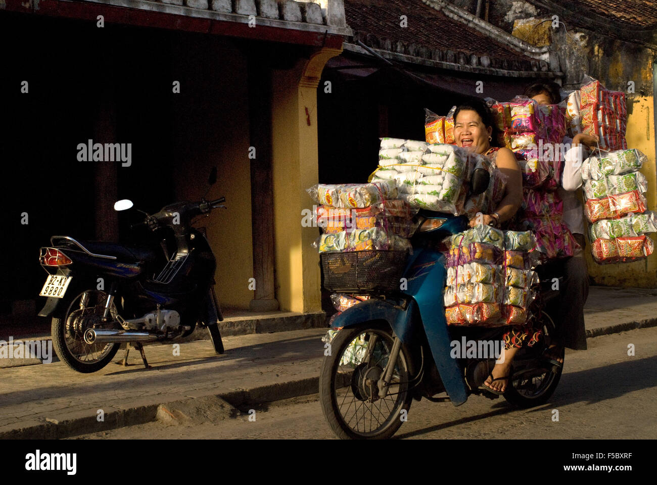 Femme la conduite d'une moto chargée à ras bord, Hoi An, Vietnam. Vietnam, Province de Quang Nam, Hoi An, Vieille Ville, classé au H Banque D'Images