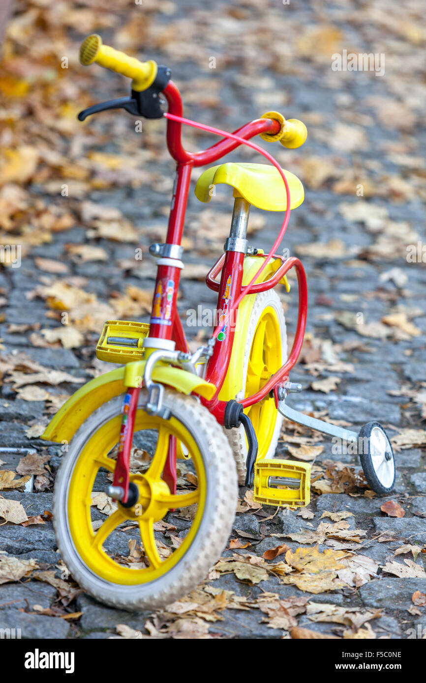 Tricycle pour enfants, vélo bébé avec stabilisateur, route d'automne, vélo pour enfants Banque D'Images