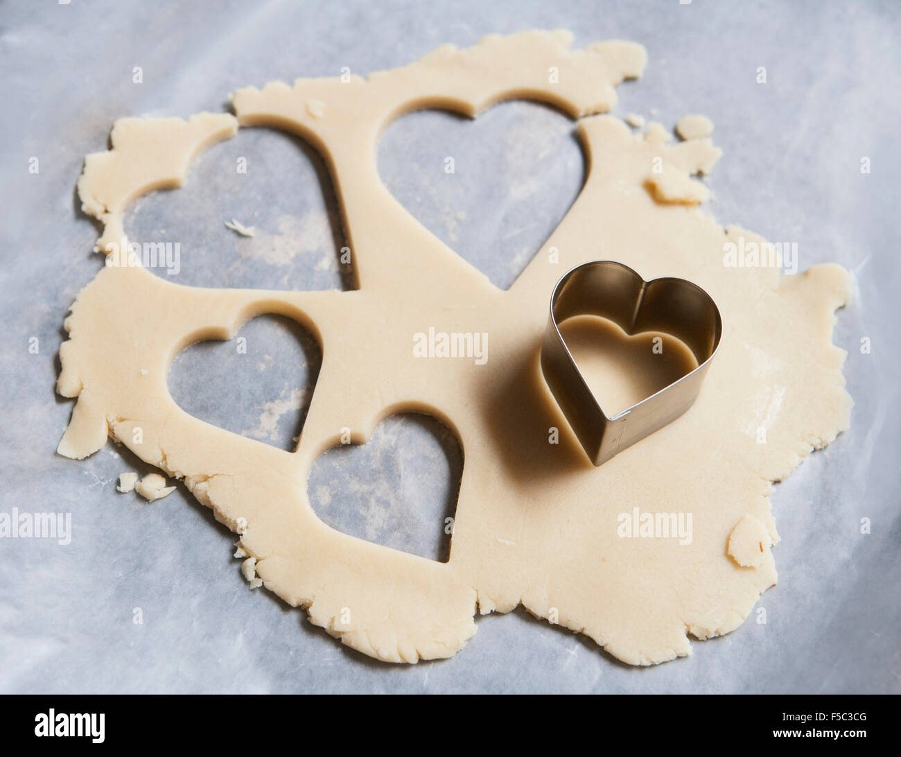 Heart-Shaped emporte-pièce et la pâte sur un papier ciré Banque D'Images