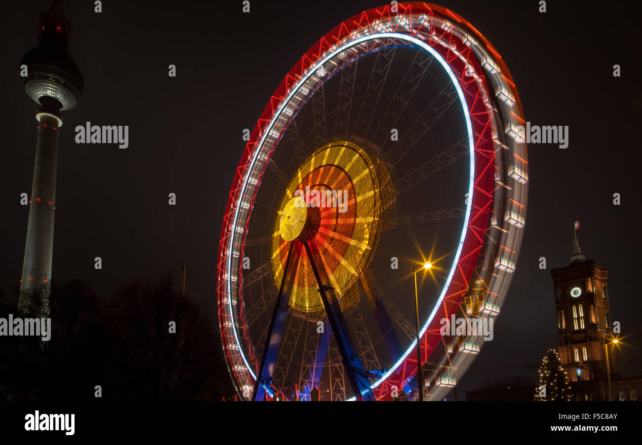 Marché de Noël, la nuit, les lumières de la grande roue en mouvement, avec l'aiguille de Berlin dans l'arrière-plan, de divertissement. Banque D'Images
