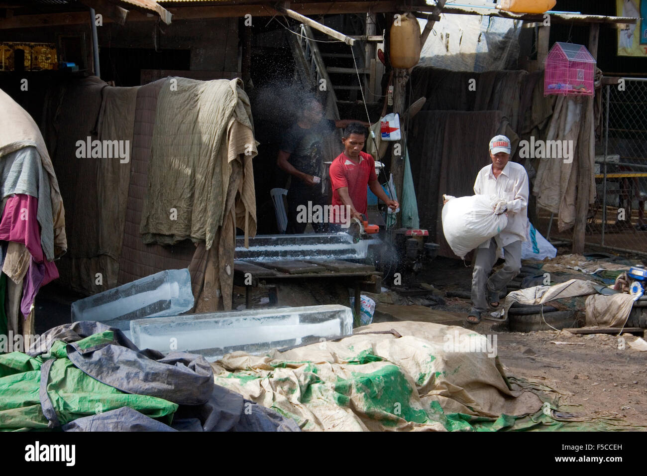 L'homme est un découpage de la glace avec une scie électrique à une entreprise de livraison de glace sur la Route Nationale 6 près de Skun, Cambodge. Banque D'Images