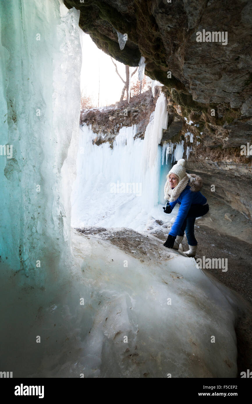 Caucasian woman in winter clothing explore derrière Chutes de Minnehaha gelés en hiver, Minneapolis, MN, USA Banque D'Images