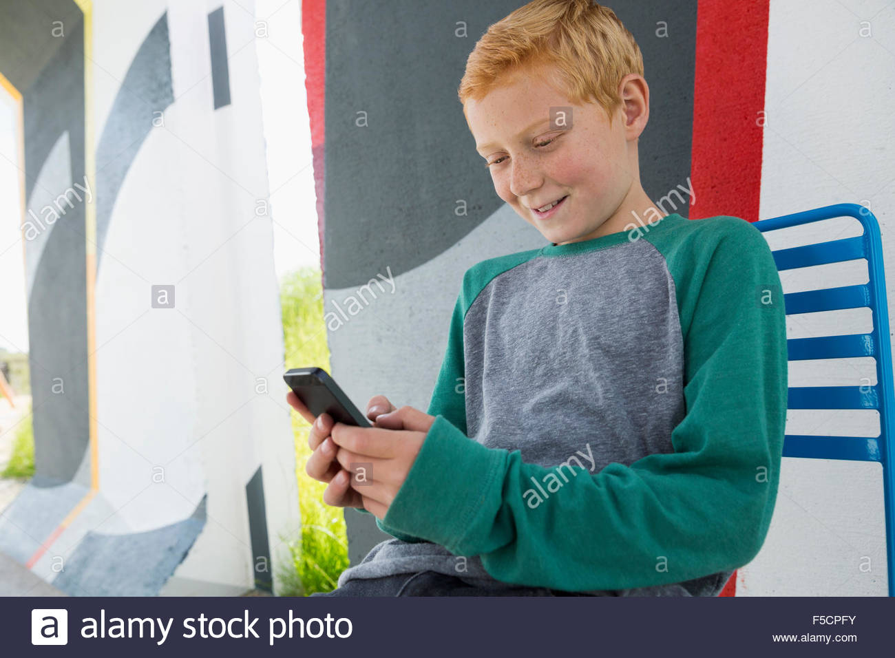 Garçon aux cheveux rouges texting with cell phone Banque D'Images