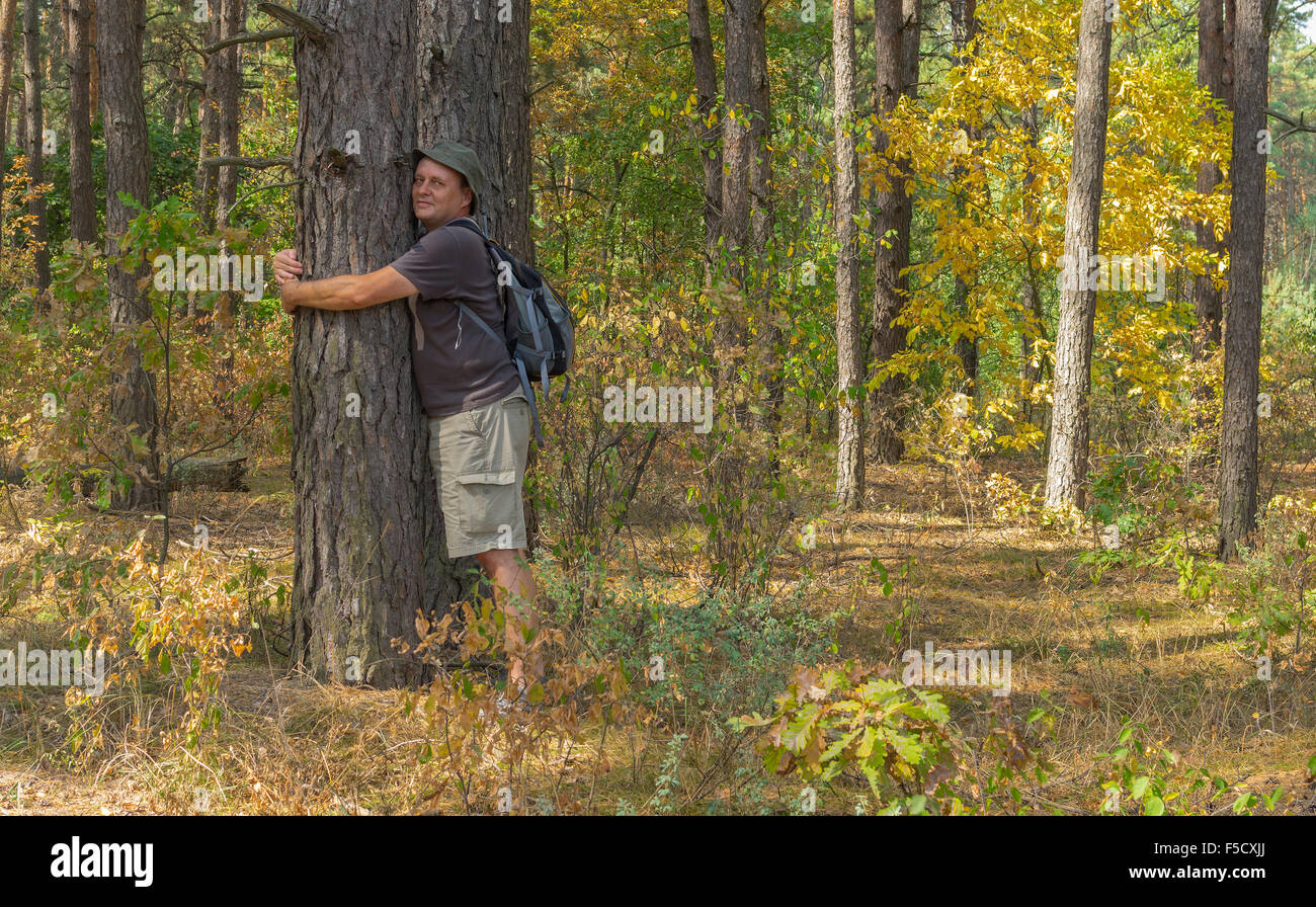 Randonneur penche d'un arbre étant de charge grâce à l'énergie positive à la forêt d'automne Banque D'Images