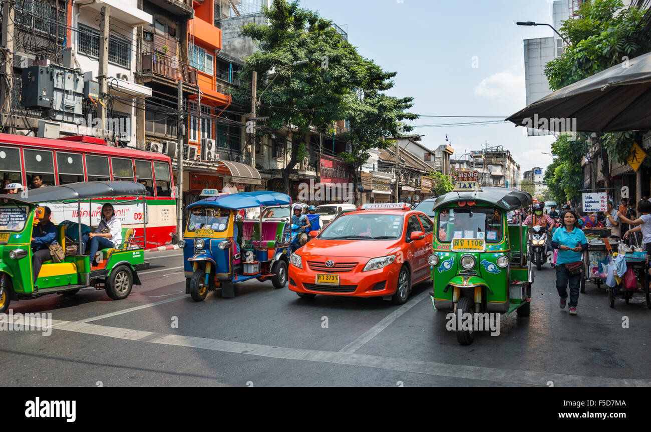 Scène de rue, tuk-tuks et des taxis qui attendent à un feu de circulation, Bangkok, Thaïlande Banque D'Images