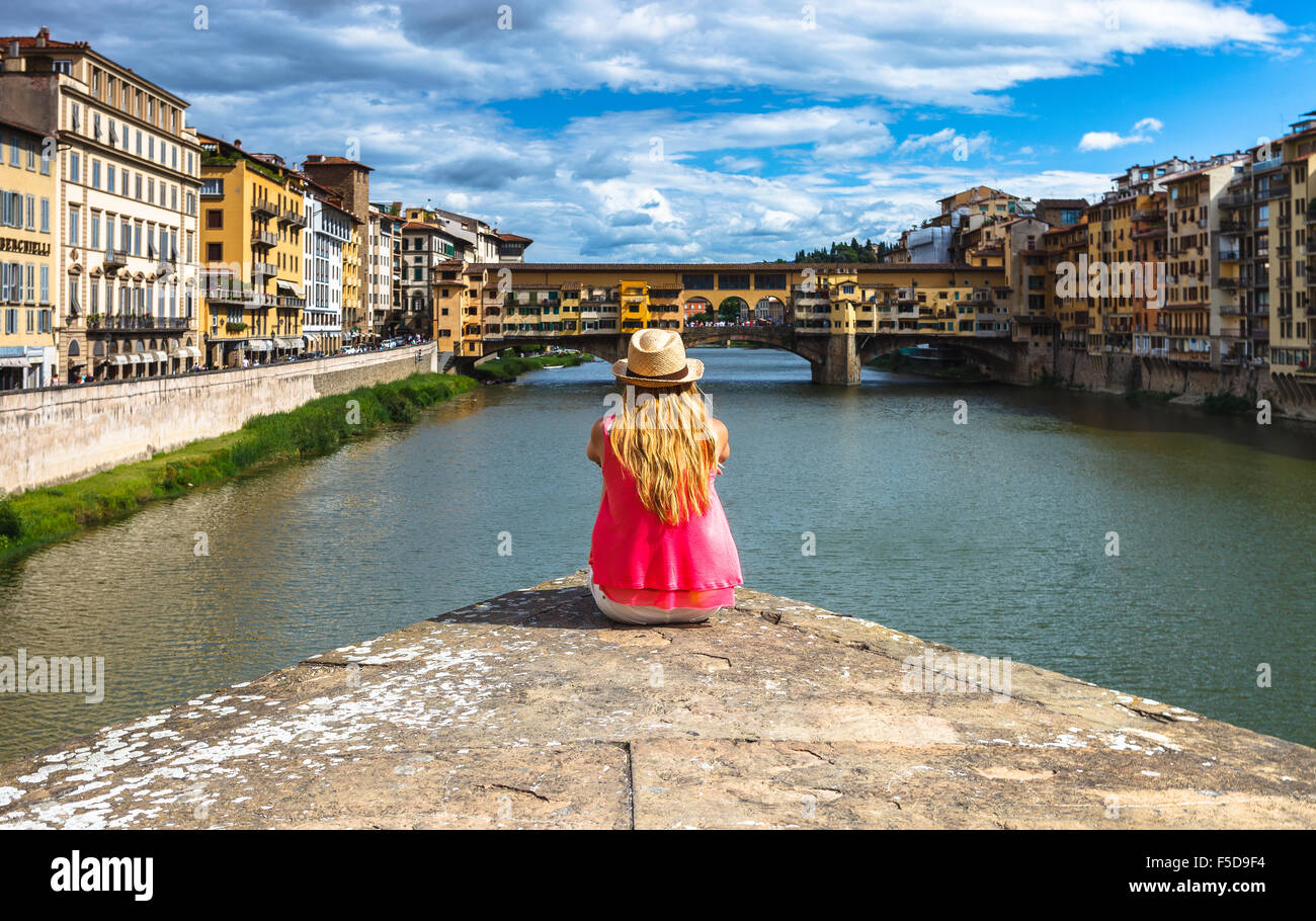 Une jeune femme en profitant de la vue sur le Ponte Vecchio et l'Arno, Florence, Toscane, Italie. Banque D'Images