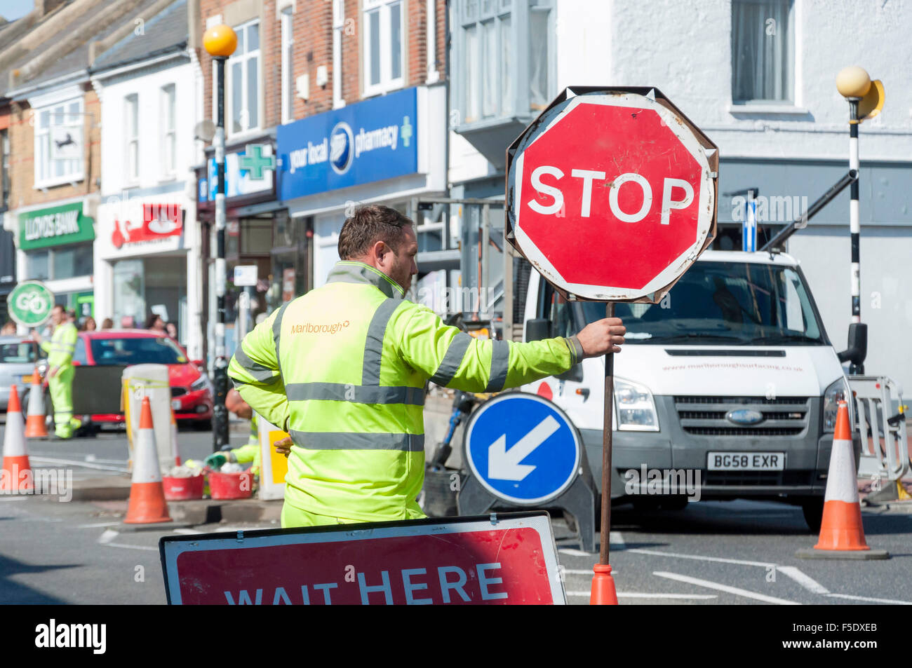 Homme tenant un panneau d'arrêt à travaux routiers, Broadway, Leigh-on-Sea, Essex, Angleterre, Royaume-Uni Banque D'Images