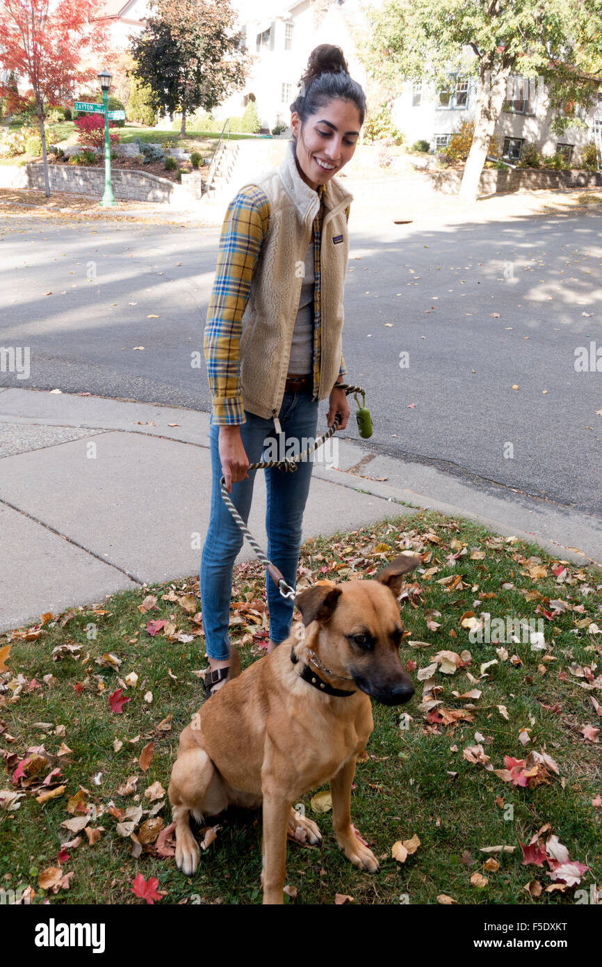 Mexican American Woman son chien en laisse sur la promenade dans un quartier résidentiel. St Paul Minnesota MN USA Banque D'Images