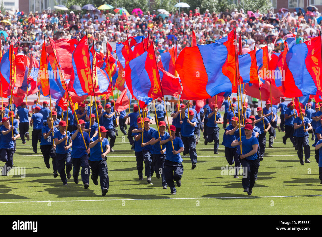 Les jeunes hommes s'exécuter avec des drapeaux de Mongolie Le Naadam, Stadium, Lantern Festival Cérémonie d'Ulaan Baatar, Oulan Bator (Mongolie), Banque D'Images