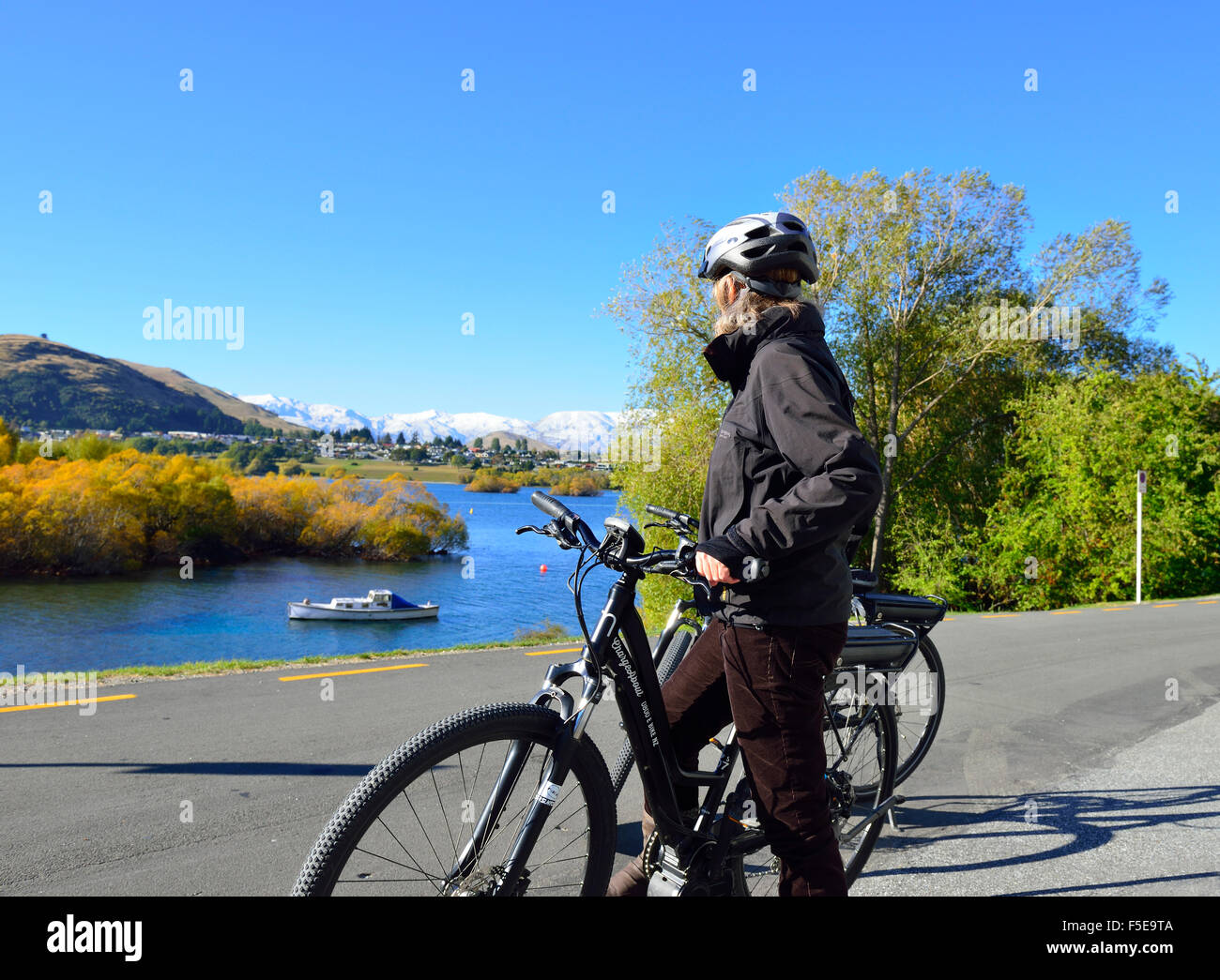 Dame cycliste sur un vélo électrique,E-Bike, regardant le paysage sur les rives du Lac Wanaka, Queenstown Frankton, Nr, île du Sud, Nouvelle-Zélande Banque D'Images