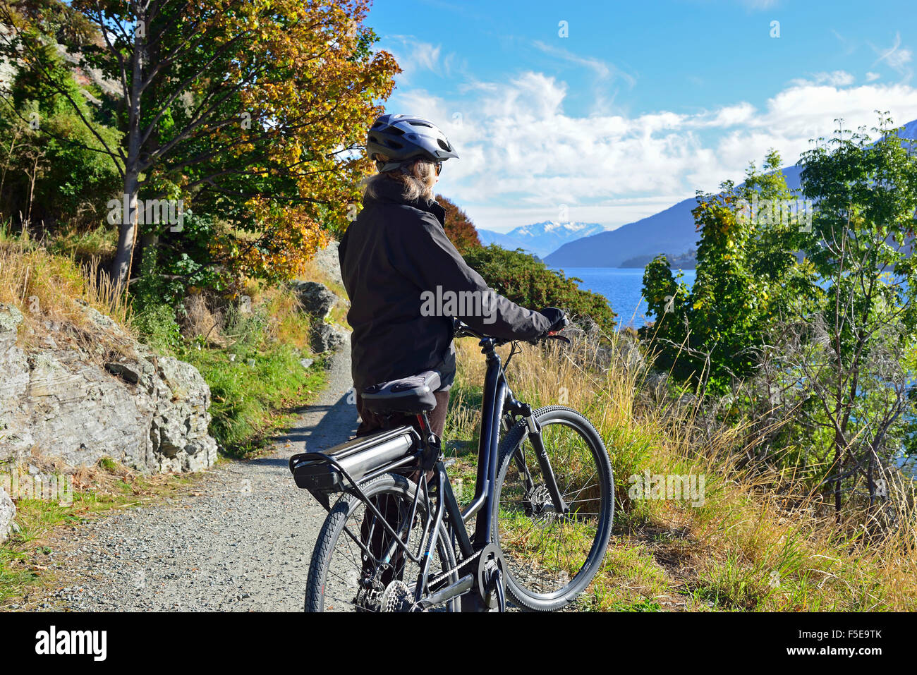 Dame cycliste sur un vélo électrique,E-Bike, regardant le paysage sur les rives du Lac Wanaka, Queenstown Frankton, Nr, île du Sud, Nouvelle-Zélande Banque D'Images