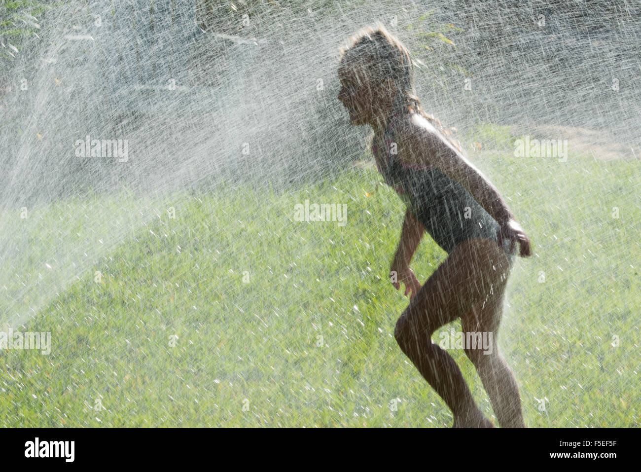 Fille jouant en aspersion d'eau Banque D'Images
