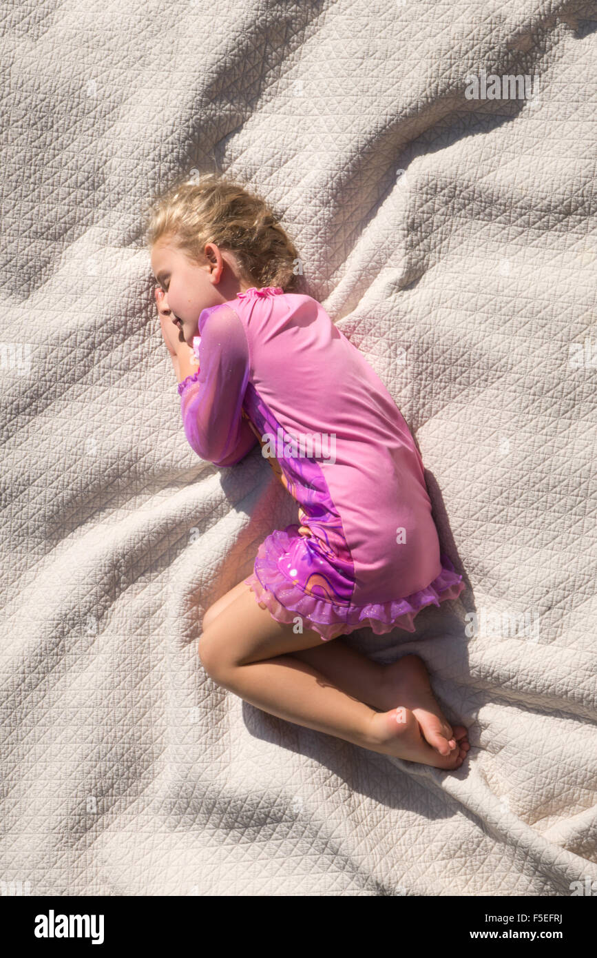 Fille dormir recroquevillé sur un lit Banque D'Images