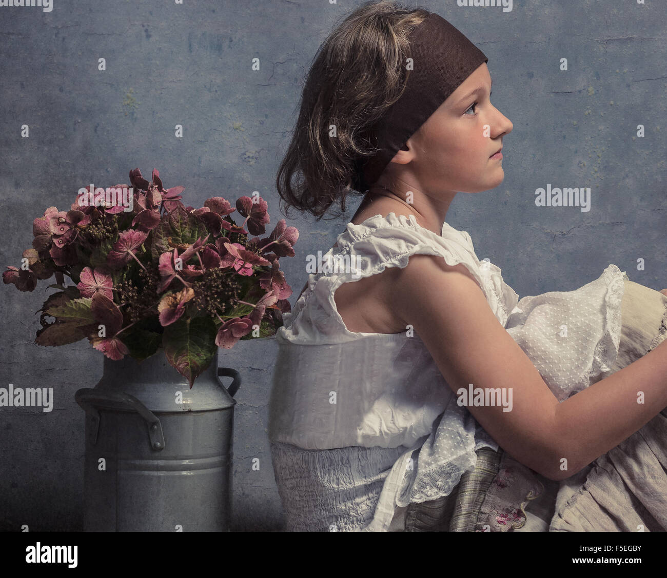Vue latérale d'une fille assise avec son dos à un pot de fleurs Banque D'Images