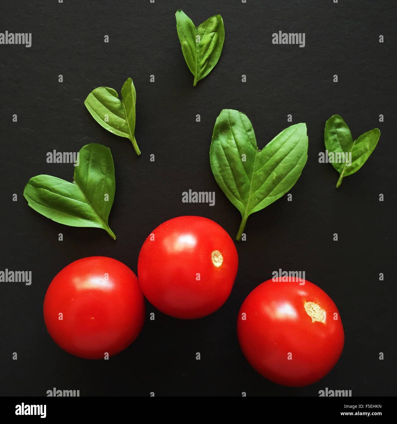 Les tomates et les feuilles de basilic dans une forme de coeur Banque D'Images