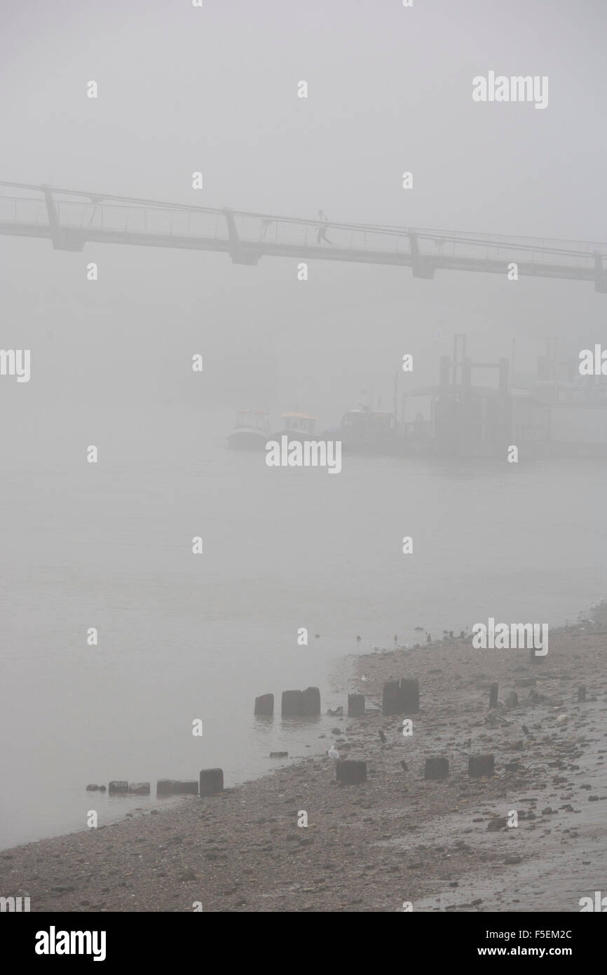 Brouillard matinal enveloppes piétons traversant la Tamise sur le pont du Millénaire. Banque D'Images
