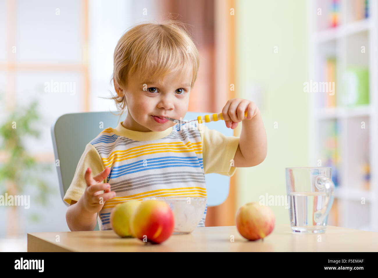 Heureux l'enfant de manger des aliments fromage avec fruits à la maison Banque D'Images