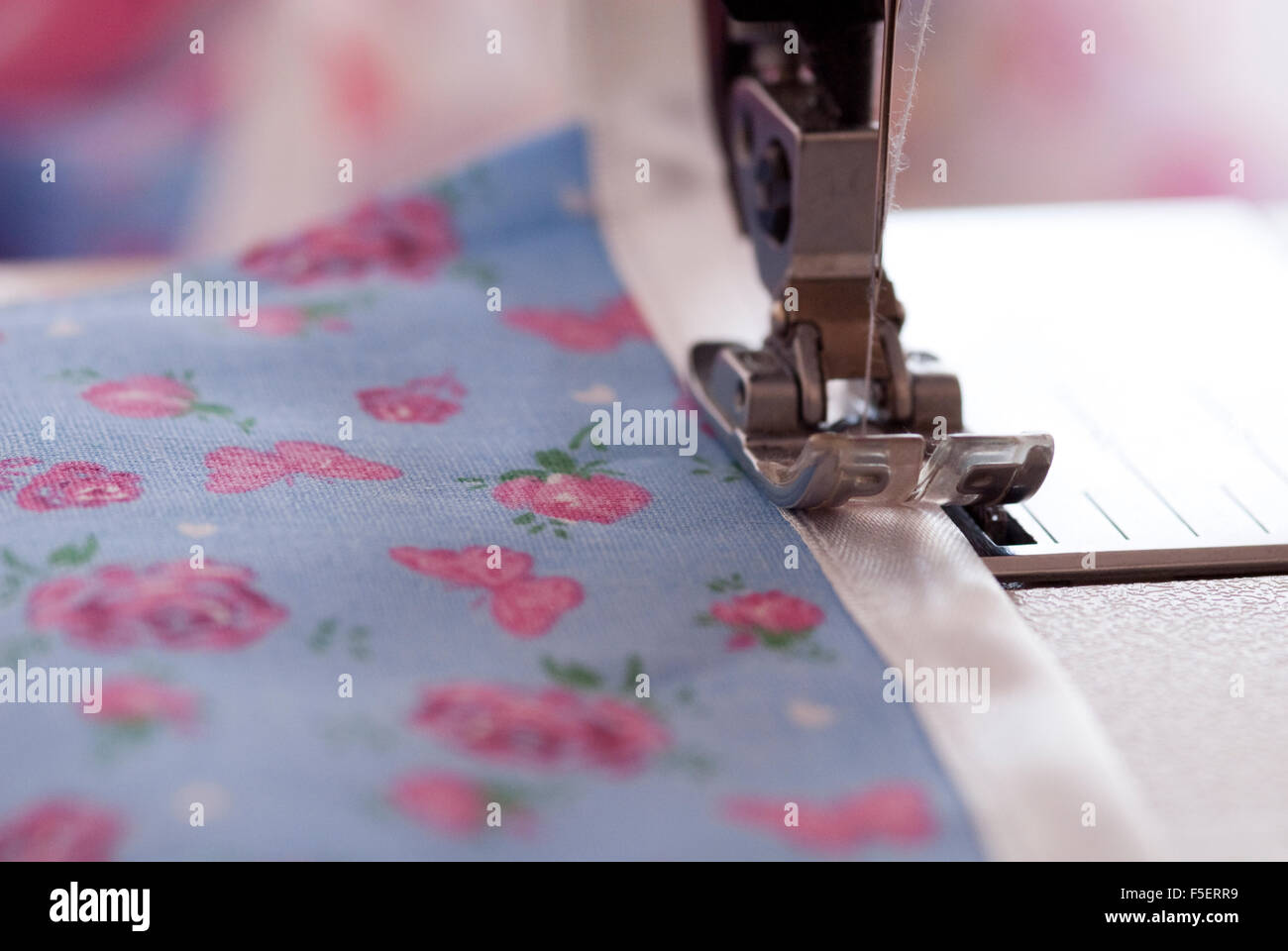 Image Concept pour la couture et décisions - gros plan d'une machine à coudre couture pied sur une jolie reliure bleu et rose tissu floral Banque D'Images