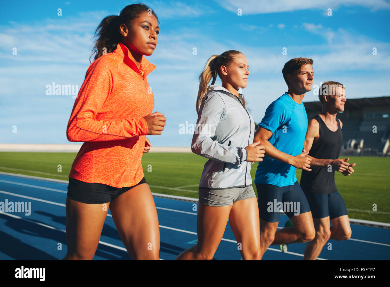 Sports divers groupe de personne pratiquant l'exécution dans le stade. Athlètes masculins et féminins exécutant ensemble sur des courses. Banque D'Images