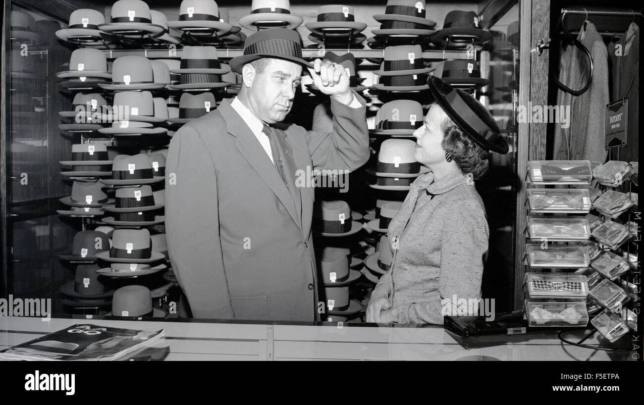 Historique Années 1950 photo à partir de l'âge d'or pour les hommes et de  chapeaux. Un homme essaye sur un chapeau dans une chapellerie avec son  épouse admiratif impressionnés par son look
